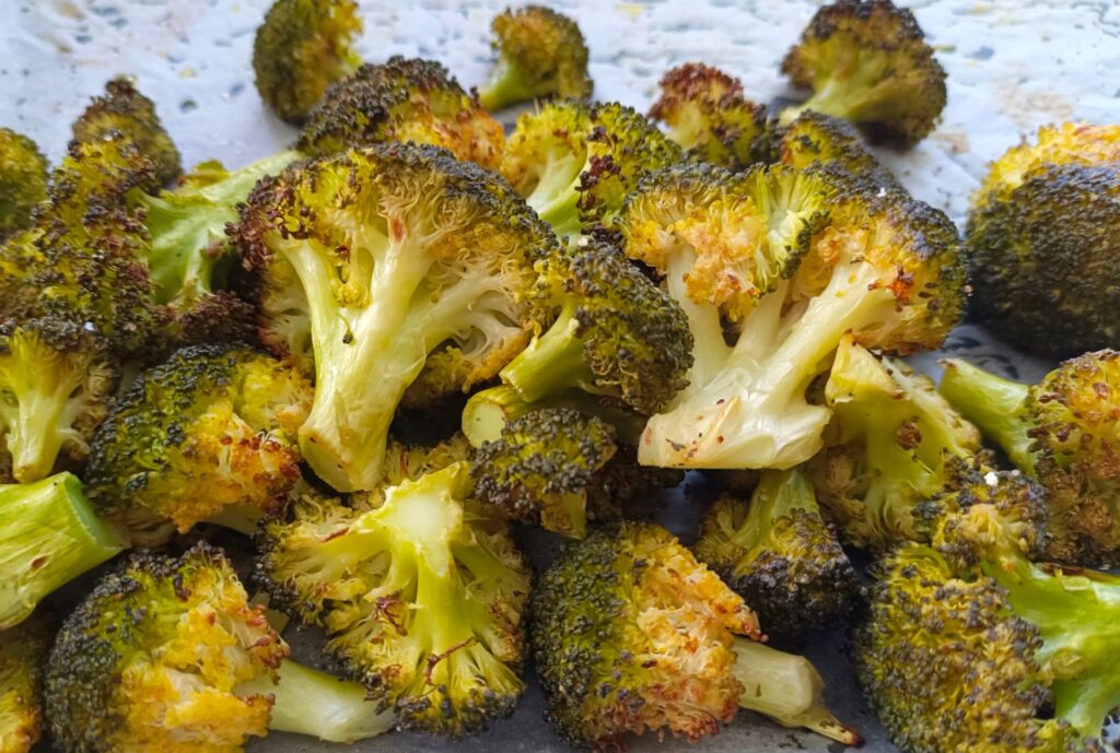 Imagen de brócoli cocinado y dorado en una bandeja de horno con papel de horno. Una opción saludable y deliciosa para disfrutar de este nutritivo vegetal. Receta de brócoli al horno de Nitka Fitness