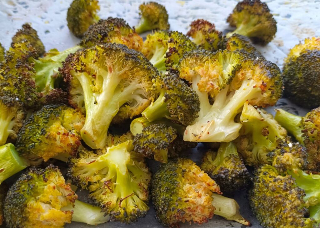 Imagen de brócoli cocinado y dorado en una bandeja de horno con papel de horno. Una opción saludable y deliciosa para disfrutar de este nutritivo vegetal. Receta de brócoli al horno de Nitka Fitness